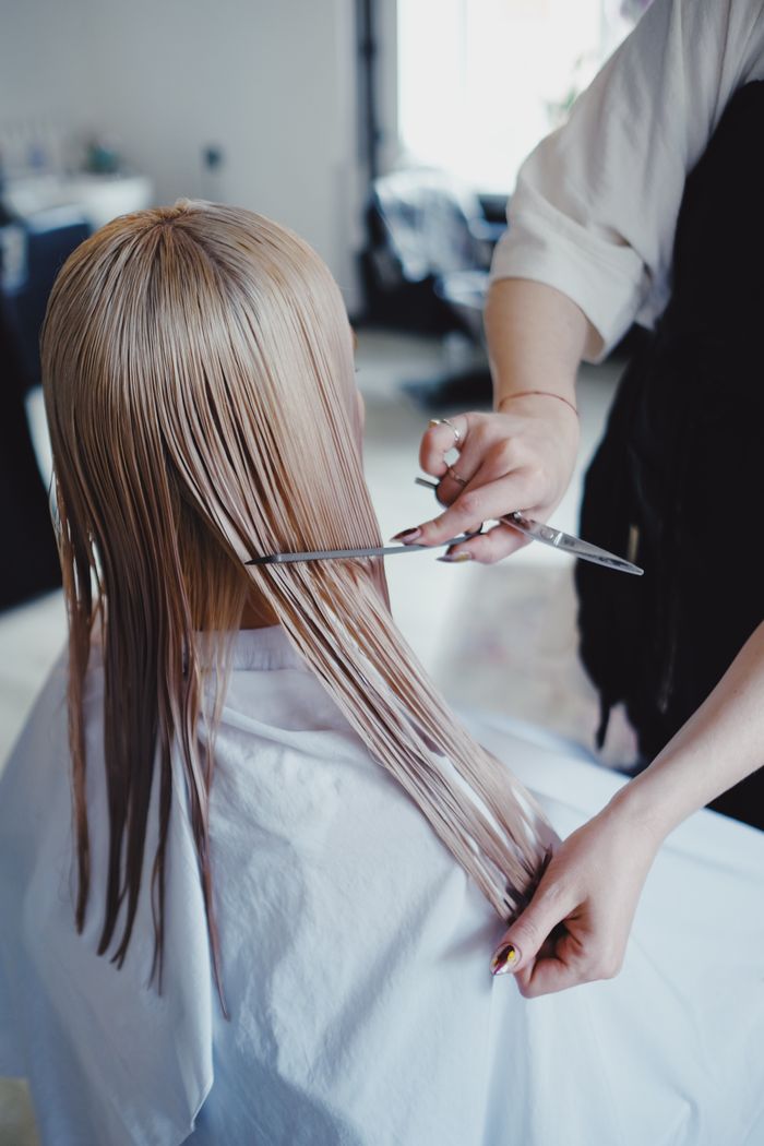 Blond woman receiving a professional haircut in a modern salon, showcasing precise scissor work.