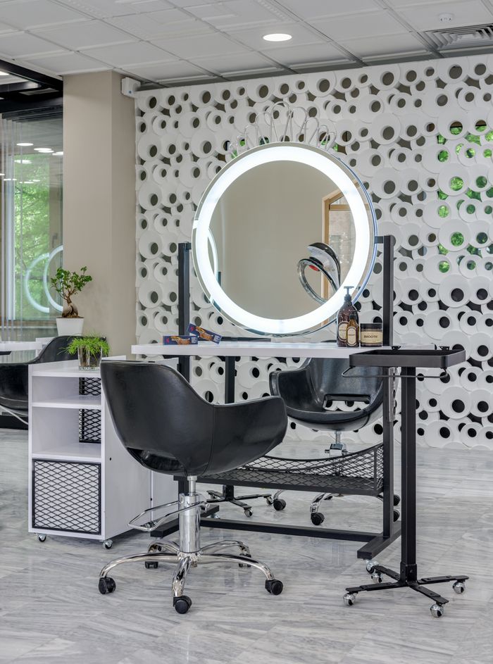 about-us-01 Chic salon setup featuring sleek chairs and illuminated vanity mirror.
